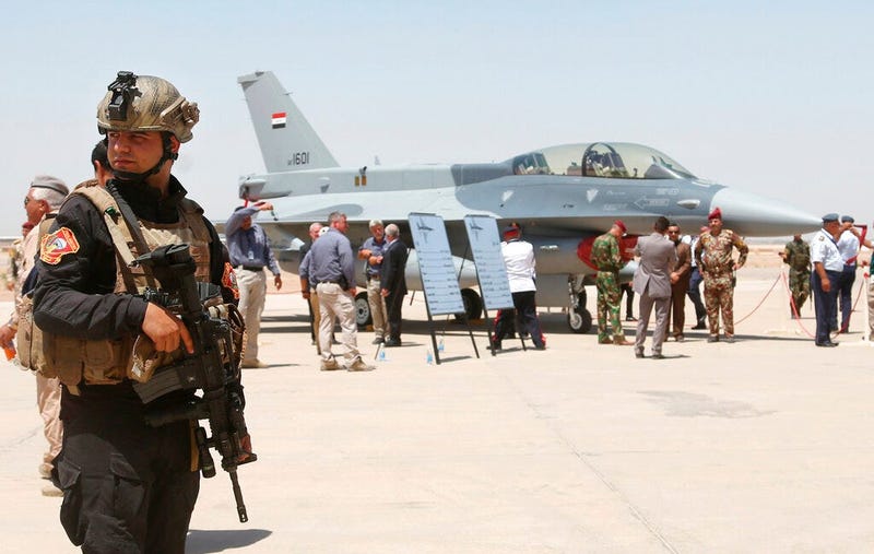 a member of the Iraqi SWAT team stands guard as security forces and others gather next to a U.S.- made F-16 fighter jet during the delivery ceremony at Balad air base, Iraq.