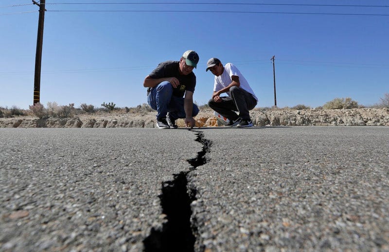 Ron Mikulaco, left, and his nephew, Brad Fernandez, examine a crack caused by an earthquake on highway 178