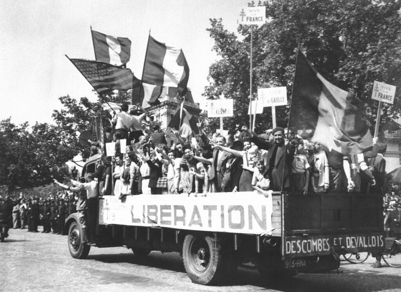 In this Aug. 28, 1944 file photo, a truck load of Parisians waving flags and carrying Vive De Gaulle banners drives through the streets