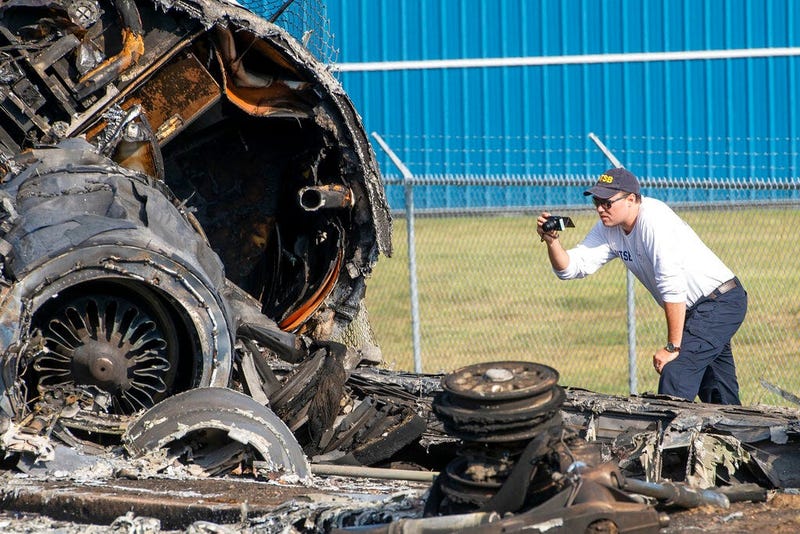 A member of the National Transportation Safety Board looks at the wreckage of a plane 
