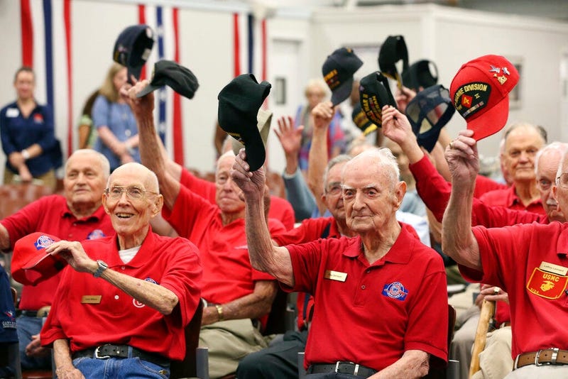 World War II veterans salute with their caps as they pose for a photograph after a ceremony at Joint Base San Antonio-Fort Sam Houston