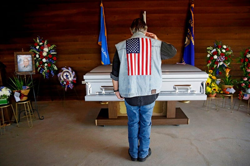 Army veteran Mike Traupman salutes the casket of World War II veteran Herman White