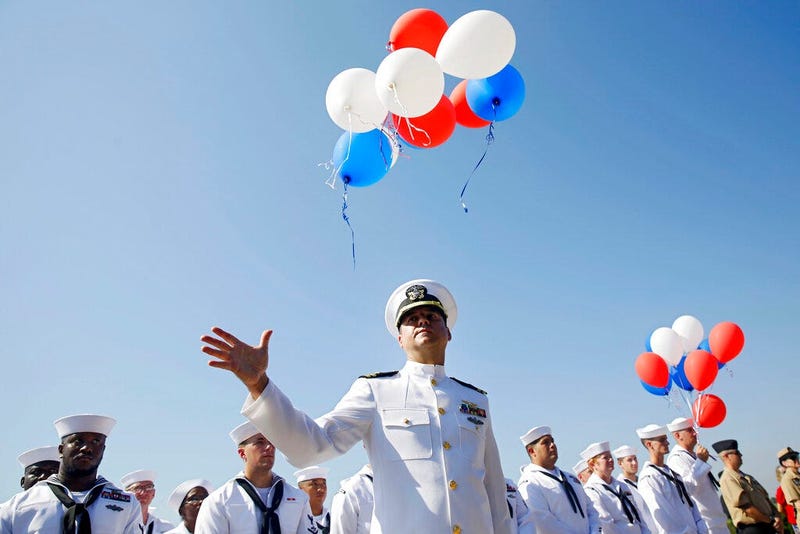 Navy Lieutenant Luke Hosman releases balloons during a funeral service for World War II veteran Herman White
