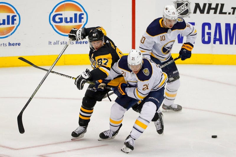 Pittsburgh Penguins' Sidney Crosby (87) and Buffalo Sabres' Kyle Okposo (21) tangle as they try to control the puck in front of Henri Jokiharju (10) during the first period of an NHL preseason hockey game, Saturday, Sept. 28, 2019, in Pittsburgh.