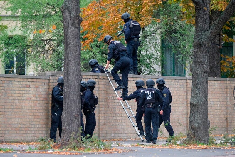 Police officers cross a wall at a crime scene in Halle, Germany, Wednesday, Oct. 9, 2019 after a shooting incident. A gunman fired several shots on Wednesday in the German city of Halle. Police say a person has been arrested after a shooting that left two