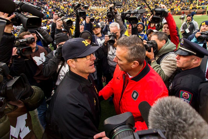 Michigan head coach Jim Harbaugh, center left, shakes hands with Ohio State head coach Urban Meyer