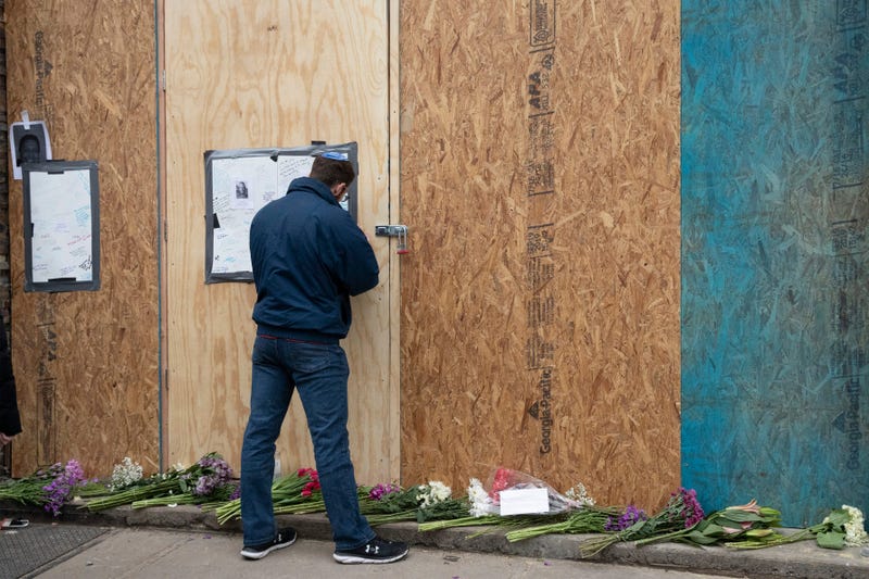 Alex Seligson pens a note of condolence Friday, Dec. 13, 2019 in Jersey City, N.J. at the boarded up kosher grocery store where three people and two gunmen were killed on Tuesday.