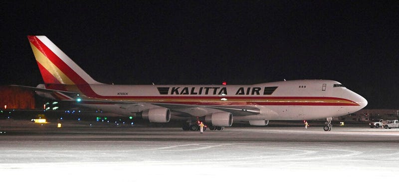An airplane, background, carrying U.S. citizens being evacuated from Wuhan, China, makes a refueling stop at the north terminal at Ted Stevens Anchorage International Airport in Anchorage, Alaska Tuesday evening, Jan. 28, 2020