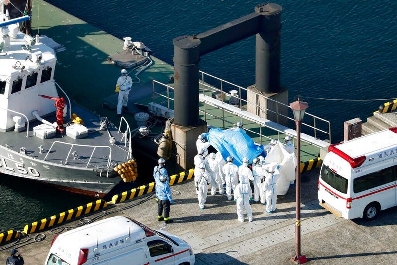 Medical workers in protective suits lead a passenger tested positive for a new coronavirus from the cruise ship Diamond Princess at Yokohama Port in Yokohama, south of Tokyo, Wednesday, Feb. 5, 2020. Japan said Wednesday 10 people on the cruise ship have 
