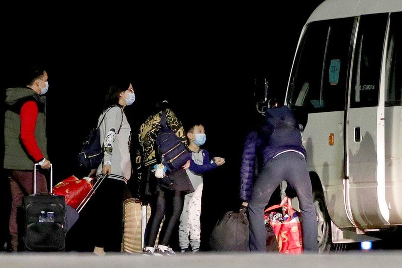 Australian evacuees board a bus after arriving at the airport on Christmas Island, Australia, early Thursday, Feb. 6, 2020. The evacuees left Wuhan, China, on an Air New Zealand rescue flight Wednesday. 