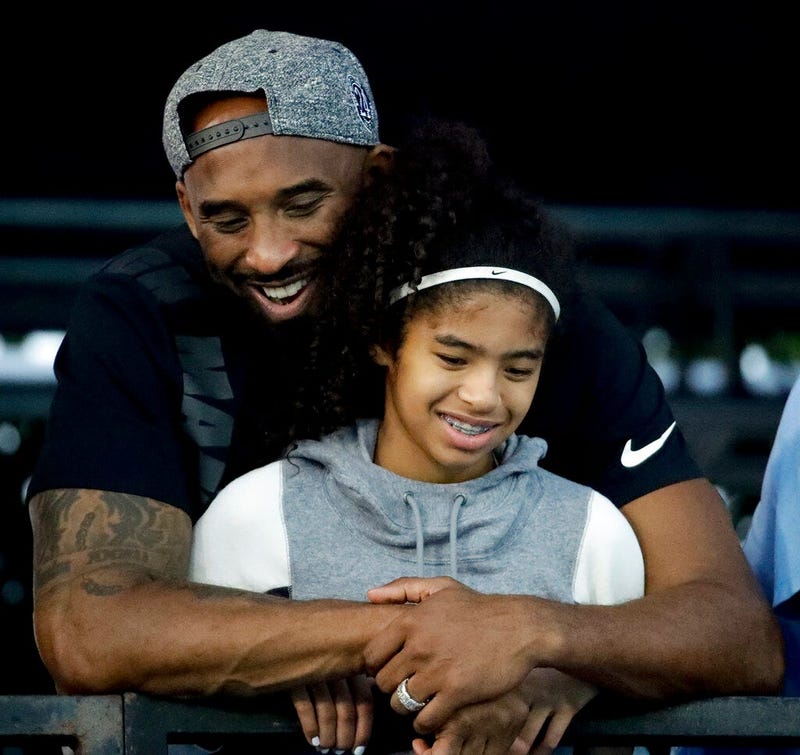 Kobe Bryant and his daughter Gianna watch during the U.S. national championships swimming meet in Irvine, Calif. Federal investigators say wreckage from the helicopter that crashed last month and killed Bryant, his daughter and seven others did not show a