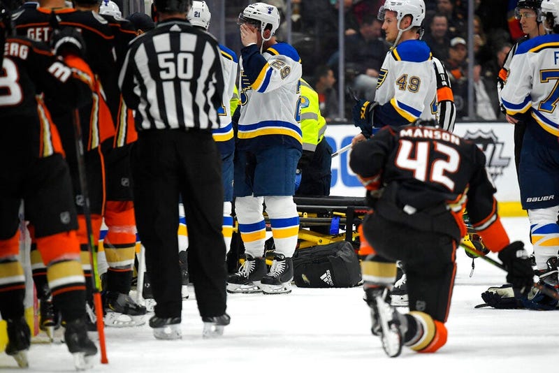 St. Louis Blues defenseman Vince Dunn, left, of center wipes his faces as Anaheim Ducks defenseman Josh Manson kneels on the ice while blues defenseman Jay Bouwmeester, who suffered a medical emergency, is worked on by medical personnel during the first p