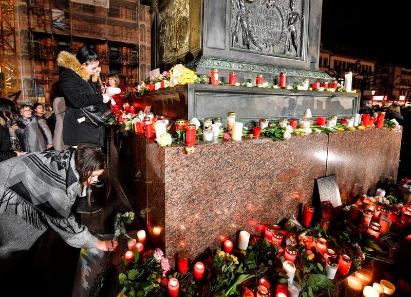 People place candles and flowers at a monument on the market place during a mourning for the victims of the shooting in Hanau, Germany, Thursday, Feb. 20, 2020. (AP Photo/Martin Meissner)