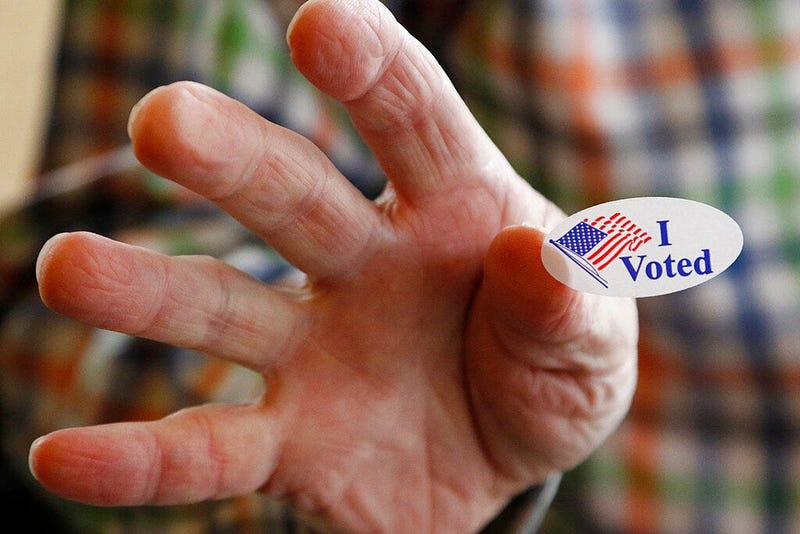 Ridgeland, Miss., precinct worker Cliff Smith offers people a "I Voted" sticker as they exit after voting in the party presidential primary, Tuesday, March 10, 2020.