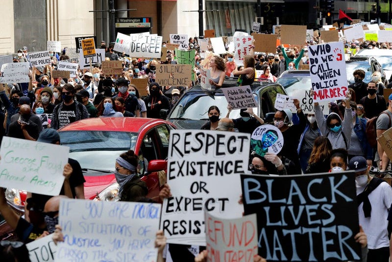People hold signs as they march in Chicago, Saturday, May, 30, 2020, during a protest over the death of George Floyd. Floyd died in Minneapolis police custody on May 25. 