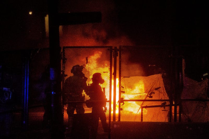 Federal officers guard the U.S. Courthouse as a fire lit by protesters burns on the other side of a perimeter fence in Portland, OreFederal officers guard the U.S. Courthouse as a fire lit by protesters burns on the other side of a perimeter fence in Port