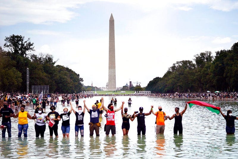 People pose for a group photo in the Reflecting Pool in the shadow of the Washington Monument as they attend the March on Washington (AP)