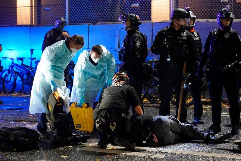 Emergency crews attend an injured man detained by police during a protest after the Nov. 3 elections in front of the east precinct station, Wednesday, Nov. 4, 2020, in Seattle