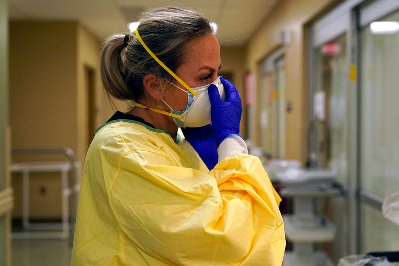 In this Nov. 24, 2020, file photo, registered nurse Chrissie Burkhiser puts on personal protective equipment as she prepares to treat a COVID-19 patient in the emergency room at Scotland County Hospital in Memphis, Mo. (AP Photo/Jeff Roberson, File)