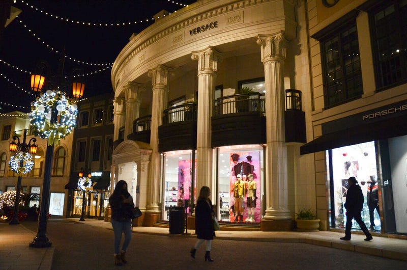 People walk near the Versace boutique on Rodeo Drive, decorated for the holidays amid the coronavirus pandemic, Monday, Nov. 30, 2020, in Beverly Hills, Calif. (AP Photo/Pamela Hassell)