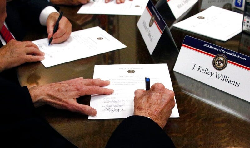 FILE - In this Dec. 19, 2016, file photo members of the Mississippi Electoral College sign certificates of vote in the process of formally casting their electoral votes in the 2016 General Election