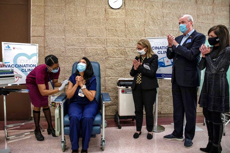 New Jersey Gov. Phil Murphy, second from right, watches as nurse Maritza Beniquez, seated, reacts after receiving the Pfizer-BioNTech COVID-19 vaccine, at University Hospital, in Newark, NJ,
