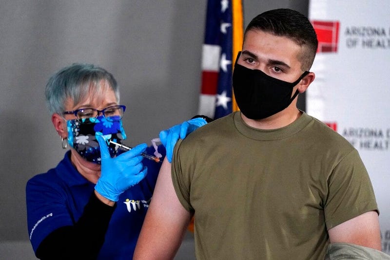 Arizona Air National Guard medic Will Smith, right, receives one of the first doses of the Pfizer-BioNTech vaccine for COVID-19 at the Arizona Department of Health Services State Laboratory from nurse Machrina Leach, Wednesday, Dec. 16, 2020, in Phoenix.