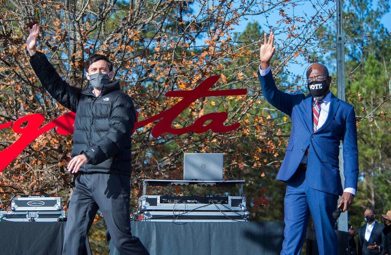 Jon Ossoff, left, and Raphael Warnock wave to the crowd during a campaign rally in Augusta, Ga., Monday, Jan. 4, 2021.