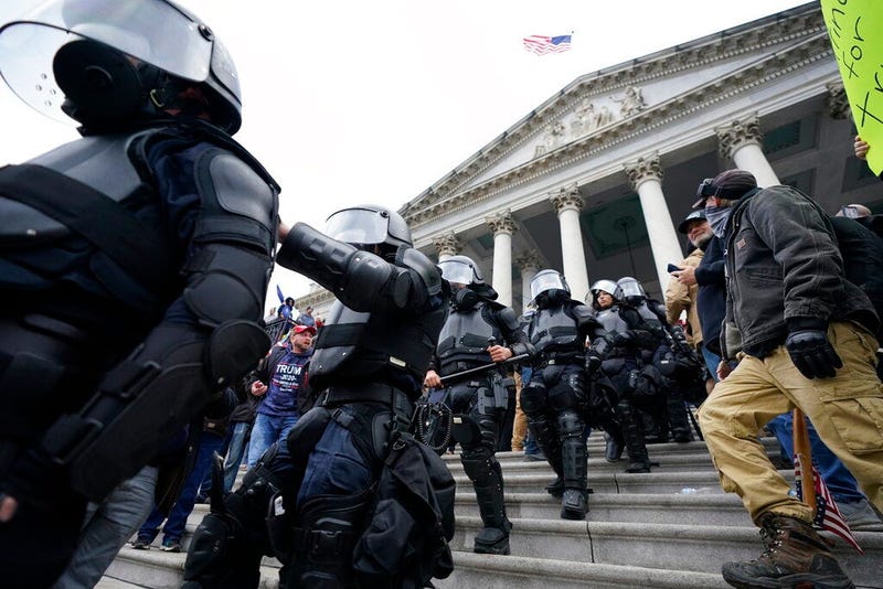 Police in riot gear walk out of the Capitol, Wednesday, Jan. 6, 2021, in Washington.