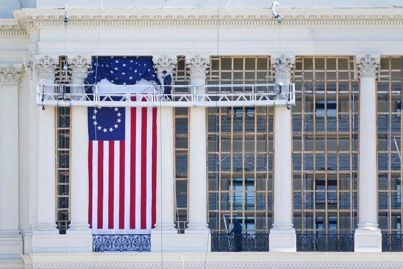 Workers install a flag on the West Front of the U.S. Capitol as preparations take place for President-elect Joe Biden's inauguration, Saturday, Jan. 9, 2021, in Washington.