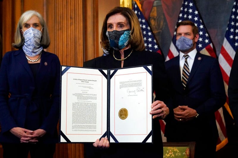 House Speaker Nancy Pelosi of Calif., displays the signed article of impeachment against President Donald Trump in an engrossment ceremony before transmission to the Senate for trial on Capitol Hill, in Washington. (AP Photo/Alex Brandon)
