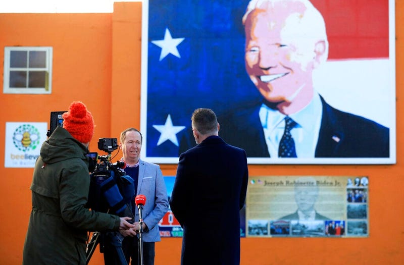 Joe Biden's cousin Joe Blewitt speaks to the media underneath his mural painted on a wall in Ballina, Ireland, Wednesday, Jan. 20, 2021. (AP Photo/Peter Morrison)
