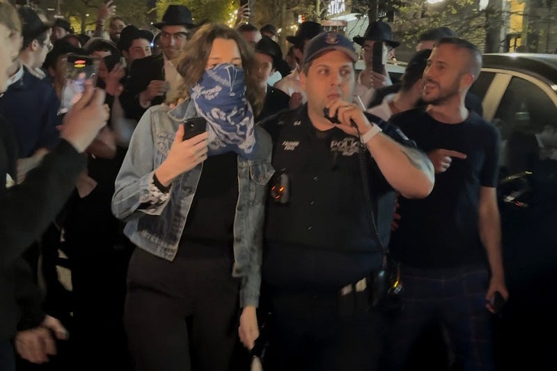 This image taken from video shows a woman and a police officer as they are pursued by a mob in the Crown Heights section of Brooklyn on Thursday, April 24, 2025