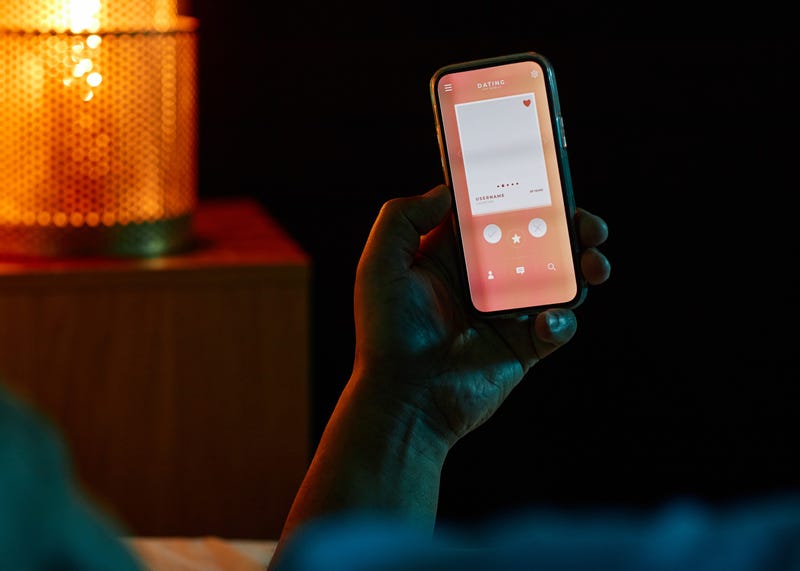 dating app on phone in dark bedroom