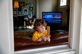 Ethan McIver, 4, son of U.S. Army Field Band member Sgt. Major Robert McIver, Jr., holds part of his toy train set as he looks out the window of his home in Catonsville, Md., Thursday, March 26, 2020. (AP Photo/Carolyn Kaster)