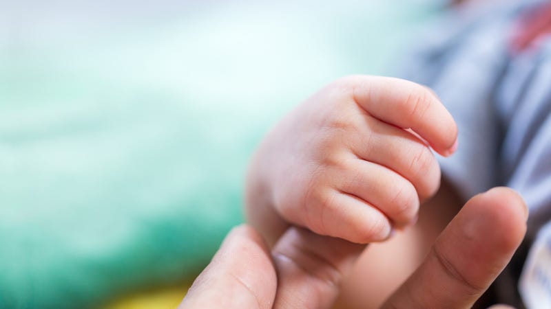 Child's hand in mother's hand on pillow