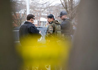 Law enforcement personnel work at the scene of a shooting, Wednesday, Feb. 12, 2020, in Baltimore. Two law enforcement officers with a fugitive task force were injured and a suspect died in the shooting. (Ulysses Muñoz/The Baltimore Sun via AP)