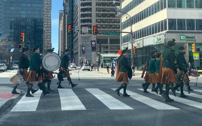 A band marching along John F. Kennedy Boulevard during the St. Patrick's Day parade