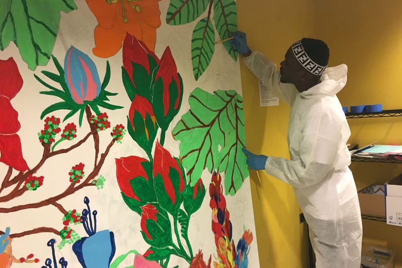 Belo, 25, paints a section of a mural as part of a Mural Arts same-day pay program.