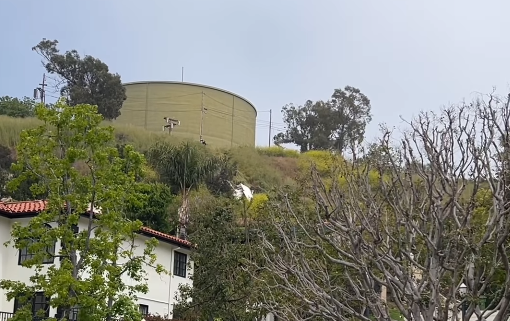 house and water tank on hillside with small white plane wreckage in the middle