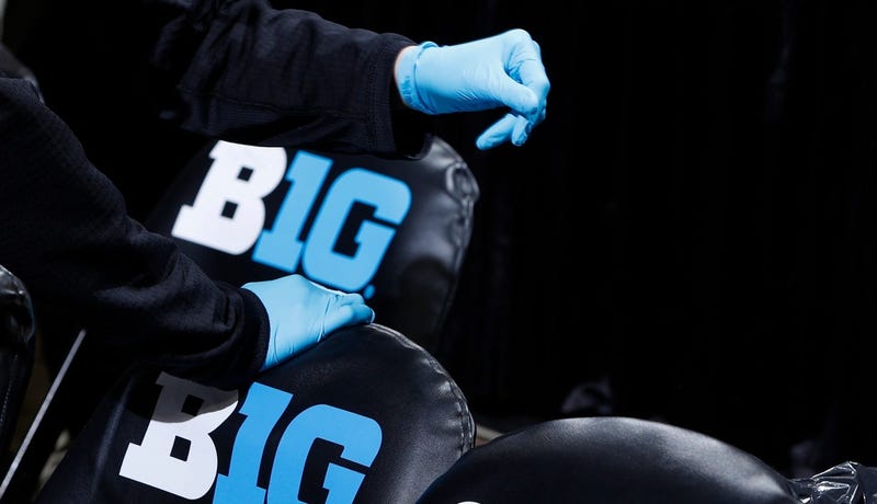 A trainer wears gloves while working around the bench area during the Big Ten Tournament.