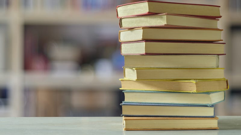 Stack of books with blurred bookshelf background - stock photo