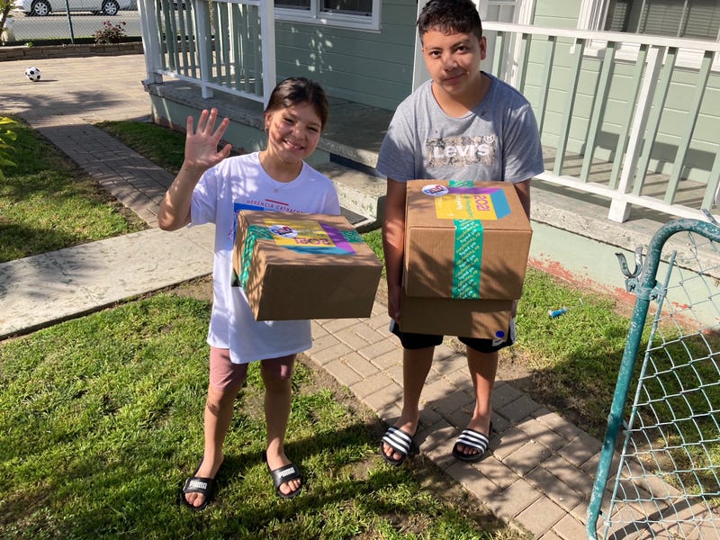Members of the Boys and Girls Clubs of Contra Costa smile with their packages in a front yard.