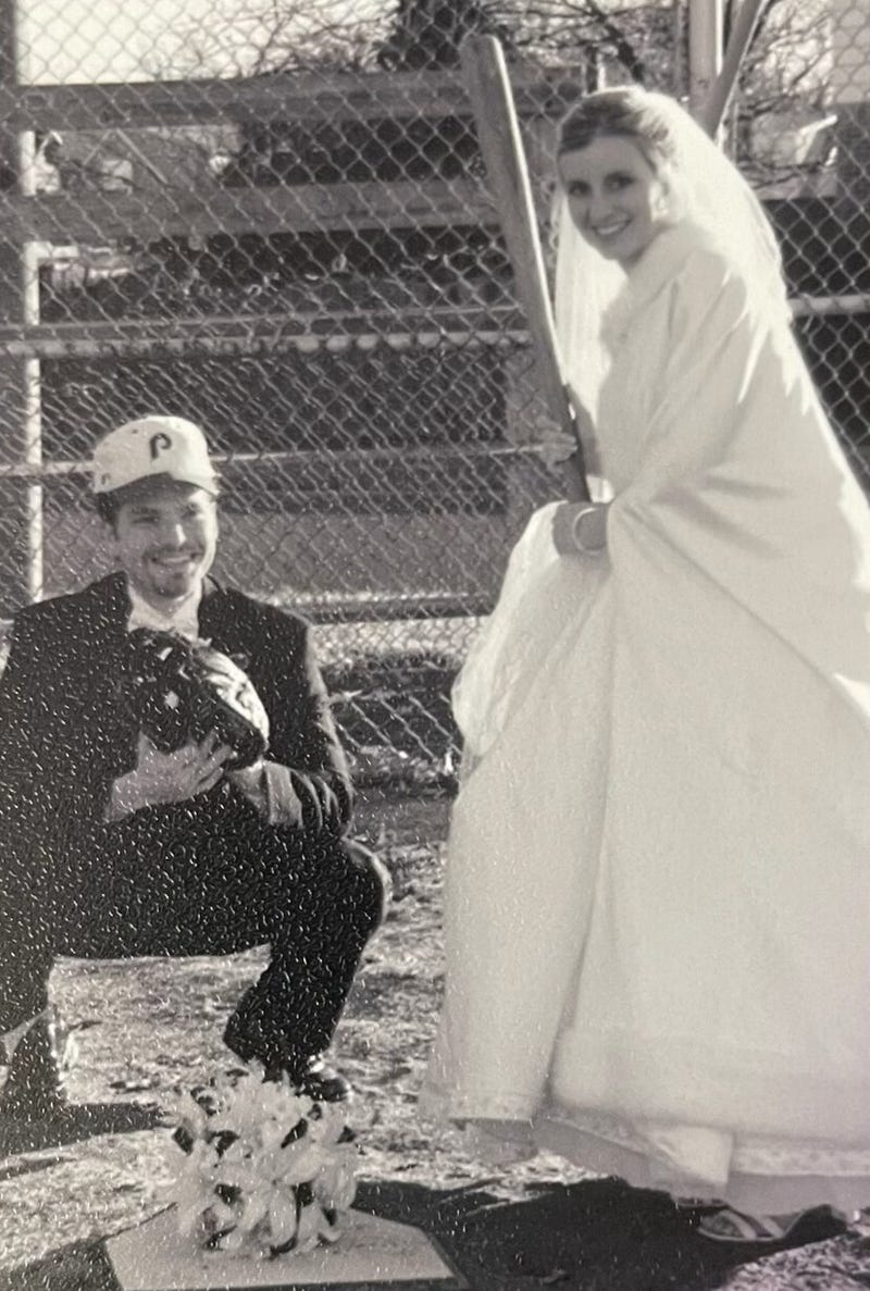 A groom and bride on home plate playing baseball.