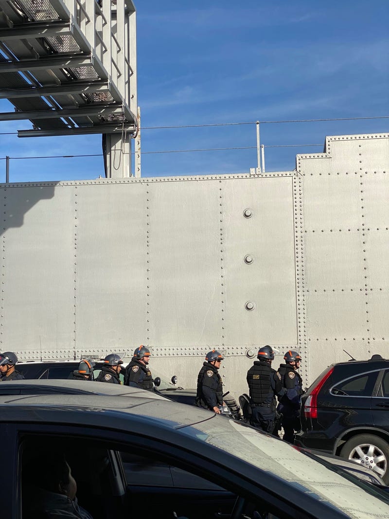 A group of officers in riot gear walk on to the Bay Bridge.