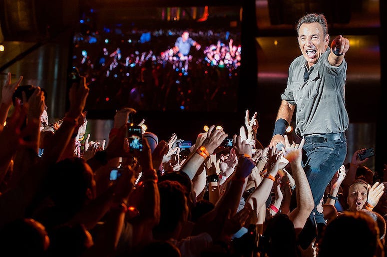Bruce Springsteen performing in concert interacting with fans.