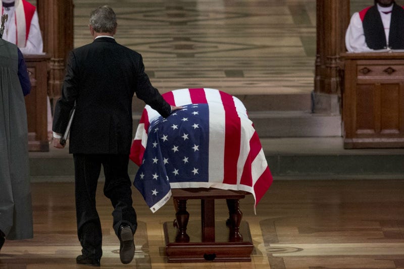 Former President George Bush touches the flag-draped casket of his father, former President George H.W. Bush, as he prepares to speak during his State Funeral at the National Cathedral, December 5, 2018 in Washington, DC.
