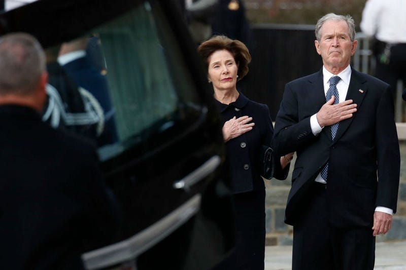 Former President George W. Bush and former first lady Laura Bush watch as the flag-draped casket of former President George H.W. Bush is carried by a joint services military honor guard to a State Funeral at the National Cathedral December 5, 2018.