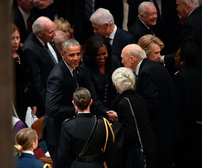 Former President Barack Obama and his wife, Michelle Obama, greet former Sen. Alan Simpson as former President George H.W. Bush before a state funeral at the Washington National Cathedral in Washington, Dec. 5, 2018.
