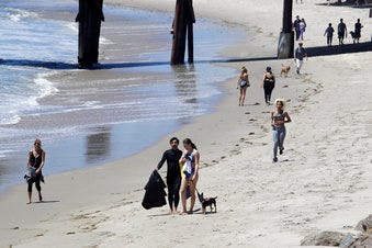 FILE - In this Wednesday, May 13, 2020, file, photo beachgoers walk and exercise on the beach in Malibu, Calif. Masks are required at Los Angeles County beaches, which reopened Wednesday. (AP Photo/Marcio Jose Sanchez, File)